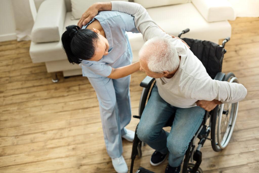 車椅子から立ち上がりを介助する介護士のイメージ